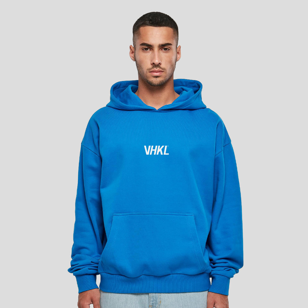 Man wearing a blue hoodie with 'VHKL' logo on a gray background